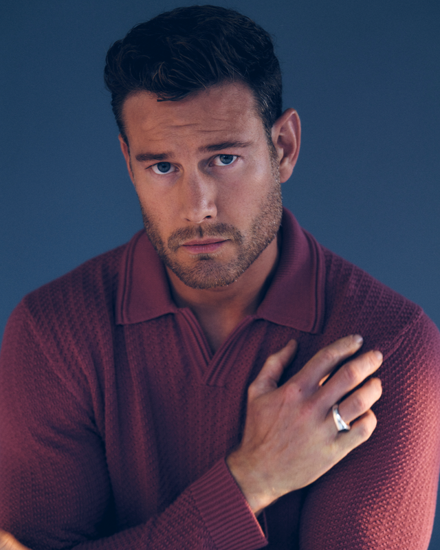 Tom Hopper wearing a maroon sweater and a Stephen Einhorn oxford inlaid signet ring against a blue background